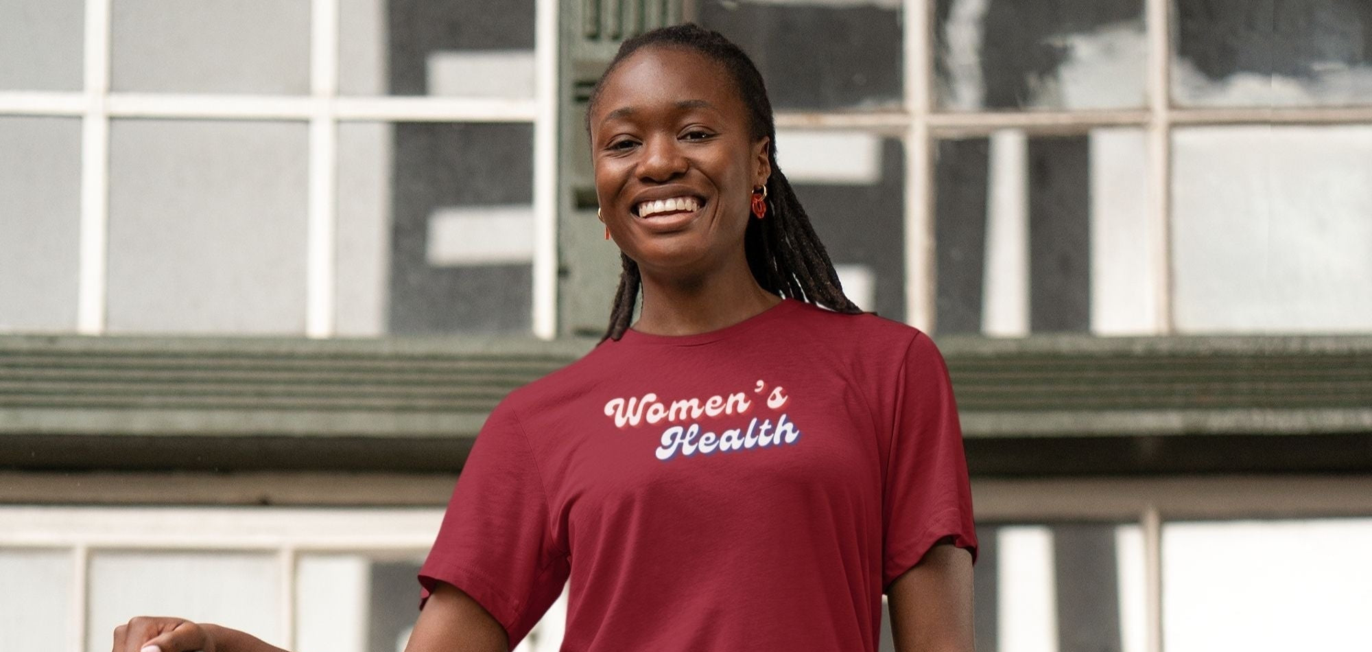 Person wearing a red 'Women's Health' t-shirt standing on metal stairs.